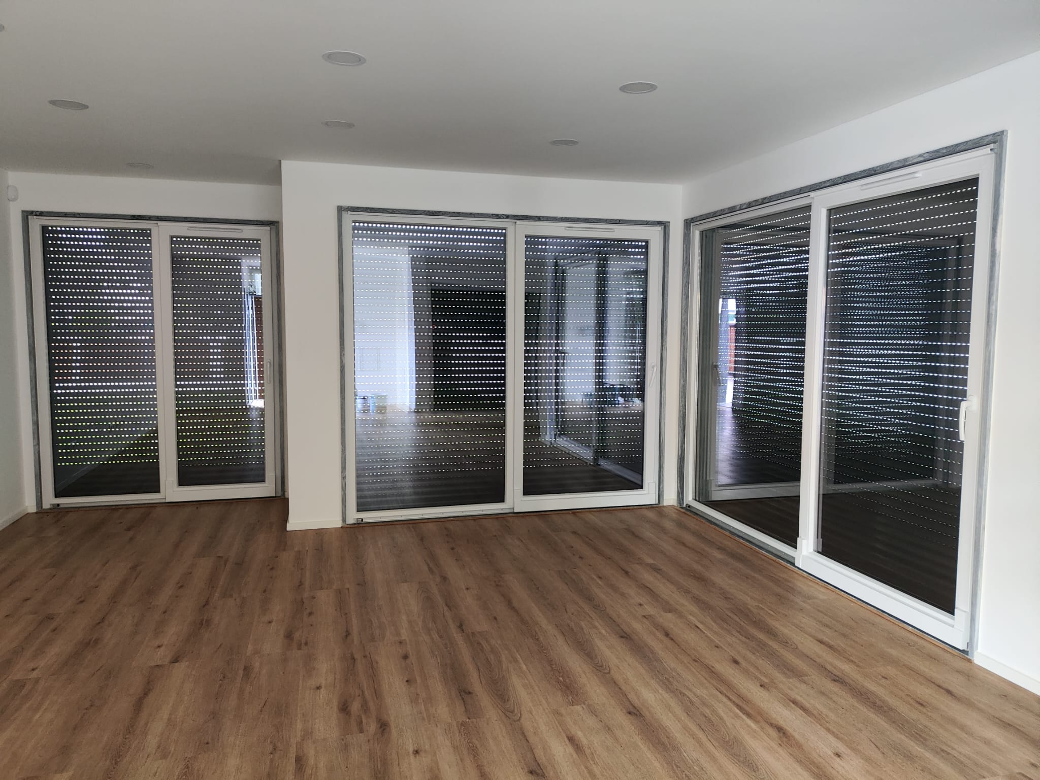 Sala ampla com grandes portas de correr e estores instalados pela TERCOMF