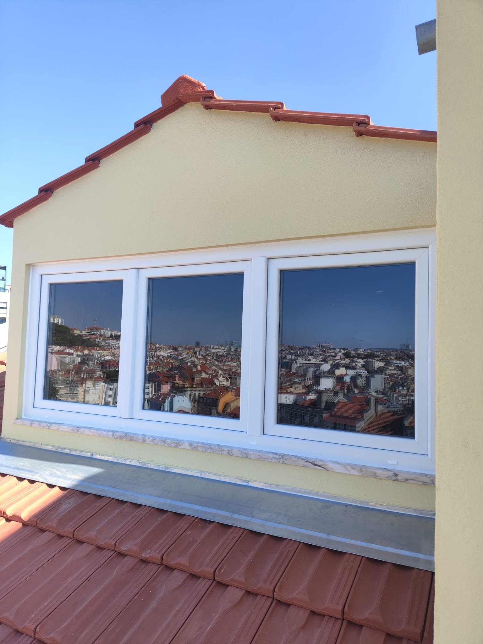 Janela em PVC instalada num sótão com vista panorâmica sobre Lisboa