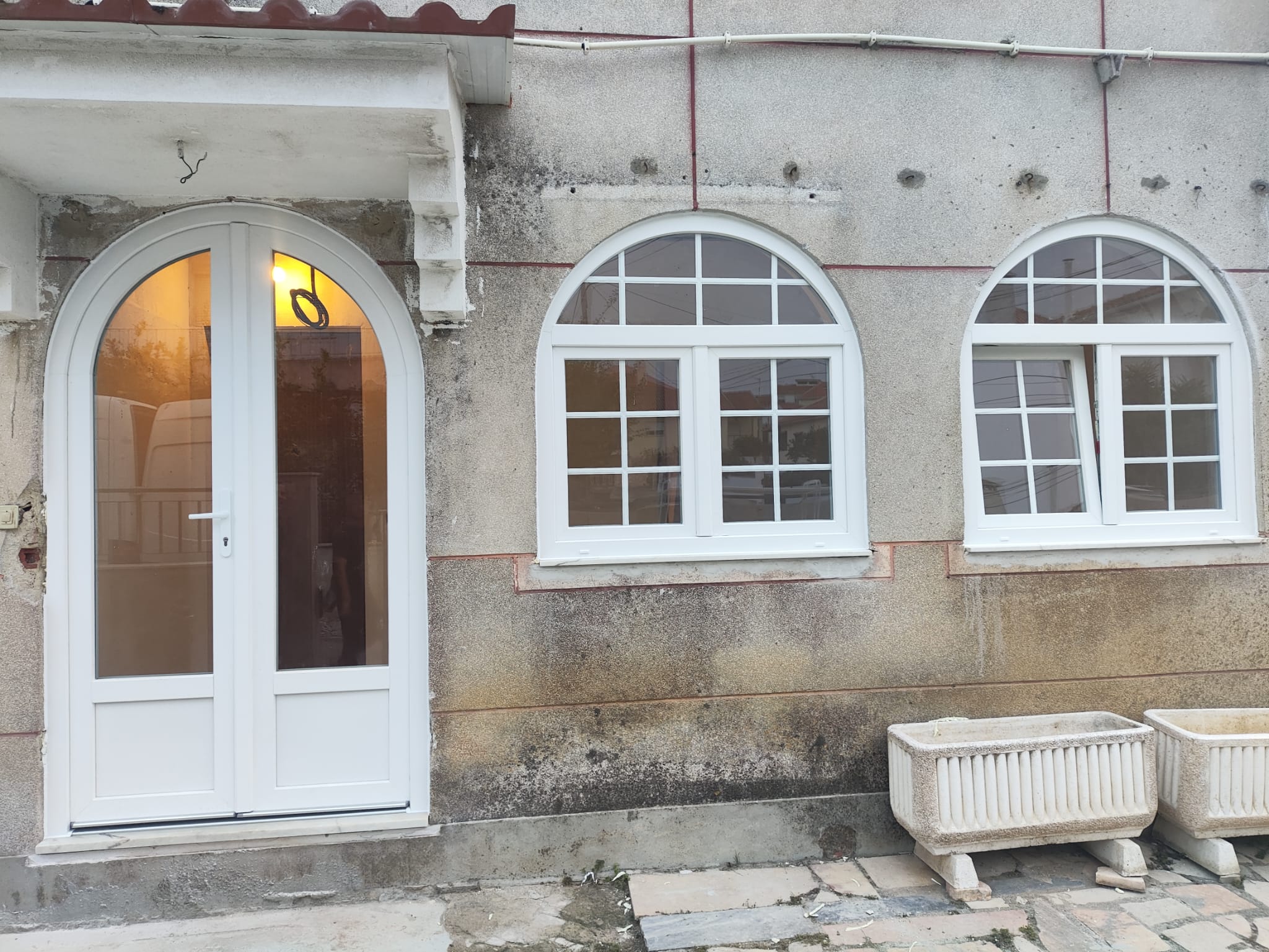 Janelas e porta arqueadas em PVC branco numa moradia